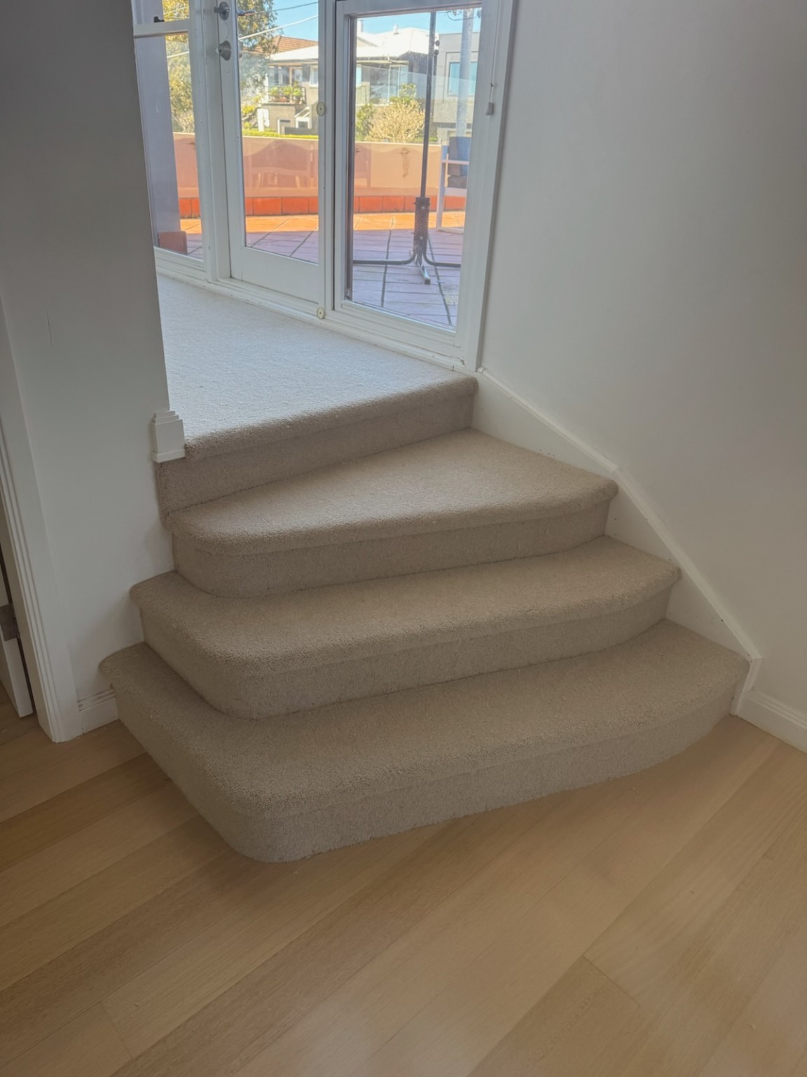 Light carpet neatly fitted to curved entry steps